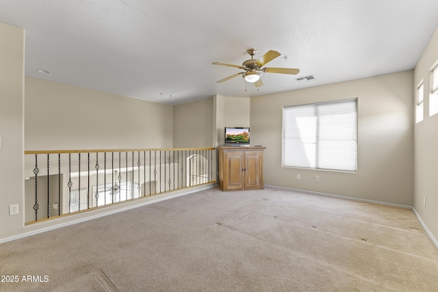 unfurnished room featuring visible vents, baseboards, ceiling fan, and a wealth of natural light