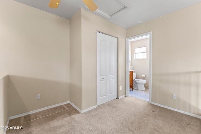 unfurnished bedroom featuring carpet floors, baseboards, ensuite bath, and a closet