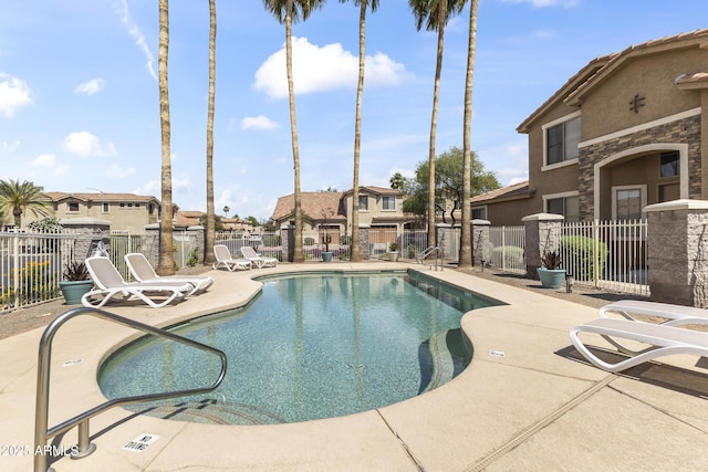community pool with fence, a patio, and a residential view