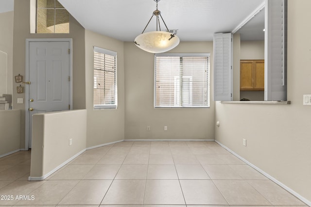 unfurnished dining area with baseboards and light tile patterned floors