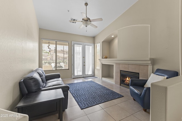 living area with tile patterned flooring, baseboards, ceiling fan, a tile fireplace, and vaulted ceiling