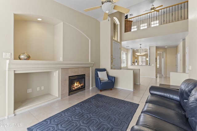 living area with tile patterned flooring, ceiling fan, baseboards, and a tile fireplace