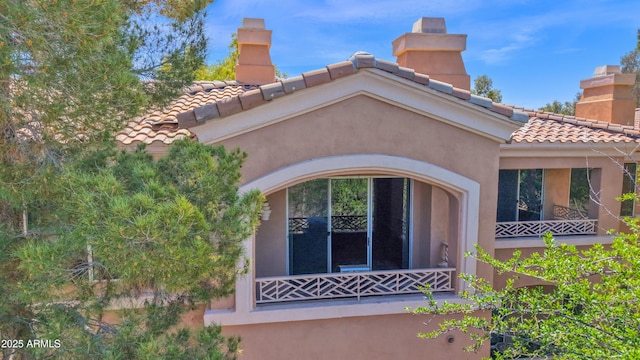 exterior space featuring a chimney, stucco siding, and a tile roof