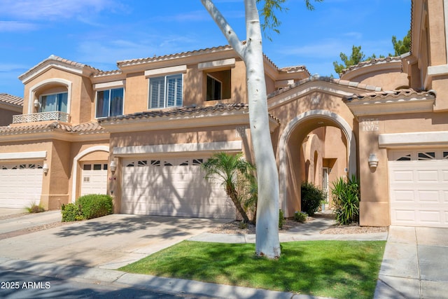 view of front of home featuring a tiled roof, a garage, driveway, and stucco siding