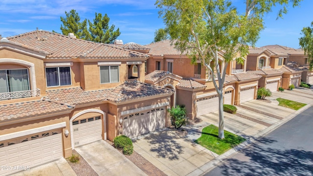 multi unit property with a tiled roof, driveway, a chimney, a garage, and stucco siding
