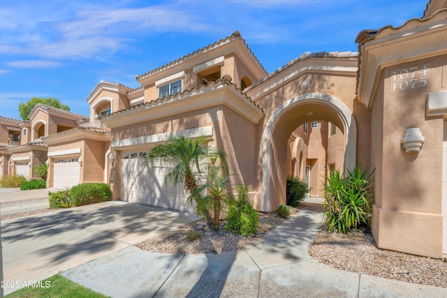 view of front of home featuring a garage, stucco siding, a tiled roof, and concrete driveway