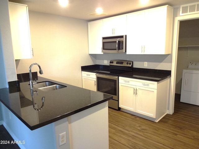 kitchen with sink, kitchen peninsula, washer / dryer, white cabinets, and appliances with stainless steel finishes