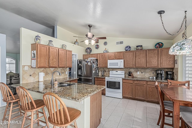 3059 E Tyson Ct, Gilbert, AZ 85295 - kitchen with white appliances, a sink, vaulted ceiling, brown cabinets, and tasteful backsplash