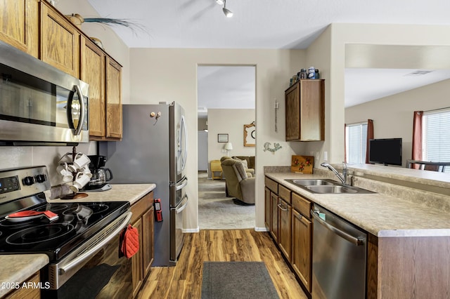 110 E Saddle Way, San Tan Valley, AZ 85143 - kitchen with stainless steel appliances, light wood-style flooring, light countertops, brown cabinetry, and open floor plan
