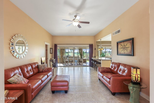 tiled living room featuring ceiling fan with notable chandelier