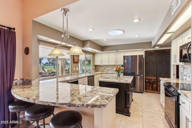 kitchen featuring black appliances, decorative light fixtures, white cabinetry, and kitchen peninsula