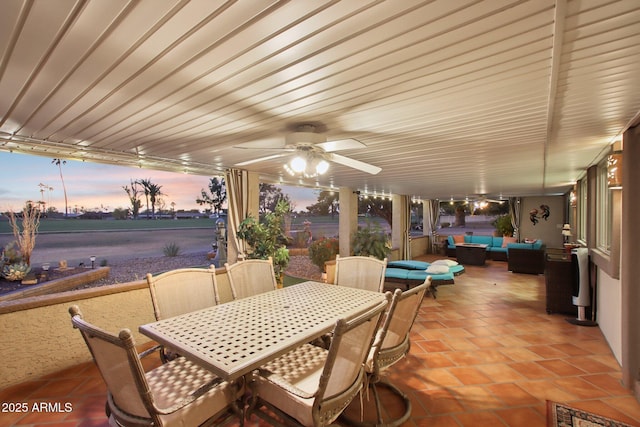 patio terrace at dusk featuring an outdoor living space, ceiling fan, and a water view