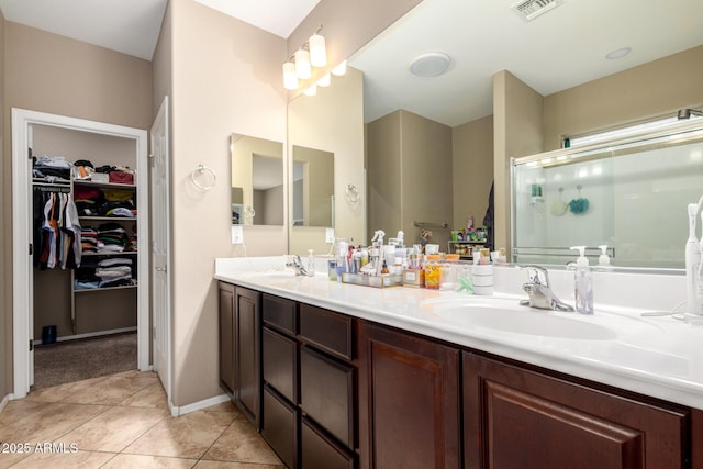 full bath featuring tile patterned floors, a stall shower, double vanity, and a sink