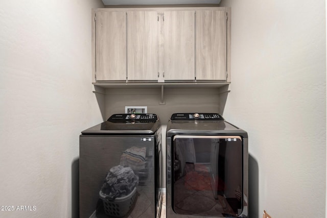 clothes washing area featuring tile patterned floors, cabinet space, and washer and clothes dryer