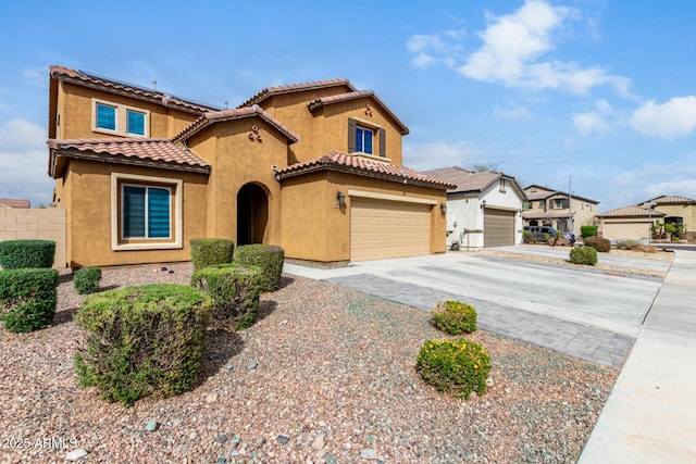 mediterranean / spanish house with fence, a tiled roof, concrete driveway, stucco siding, and a garage