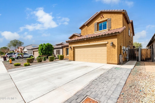 view of front of house featuring stucco siding, a tiled roof, concrete driveway, and a gate