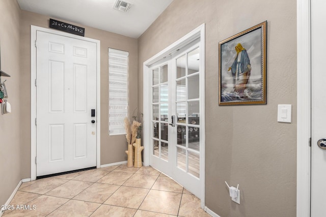 entrance foyer featuring light tile patterned floors, visible vents, and baseboards