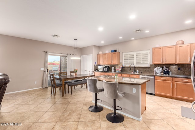 kitchen featuring dark stone counters, hanging light fixtures, stainless steel dishwasher, tasteful backsplash, and a kitchen island