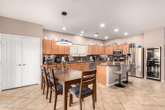 kitchen featuring decorative backsplash, decorative light fixtures, stainless steel appliances, and a kitchen island