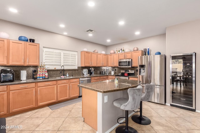 kitchen featuring dark stone counters, sink, wine cooler, appliances with stainless steel finishes, and a kitchen island