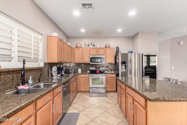 kitchen featuring dark stone countertops, a center island, sink, and stainless steel appliances