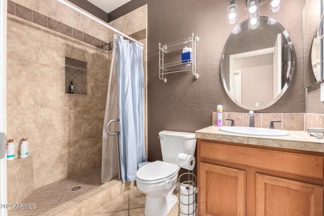 bathroom with tile patterned floors, vanity, toilet, and curtained shower