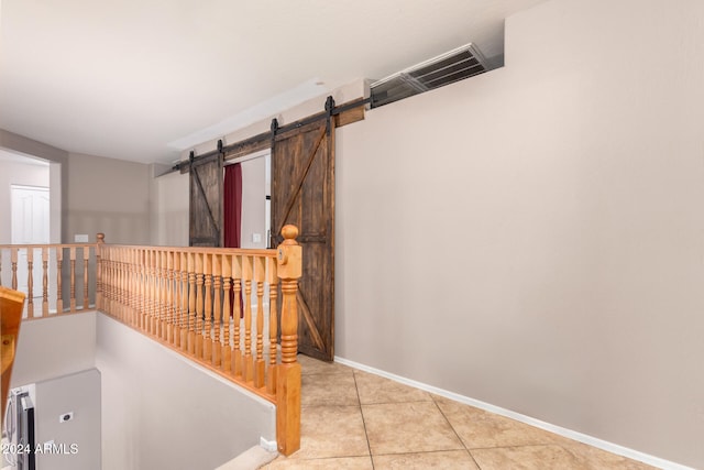 hall featuring a barn door and light tile patterned floors