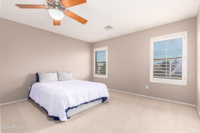 carpeted bedroom with multiple windows and ceiling fan