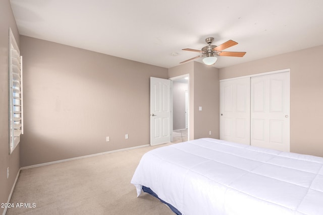 bedroom with ceiling fan, a closet, and light carpet