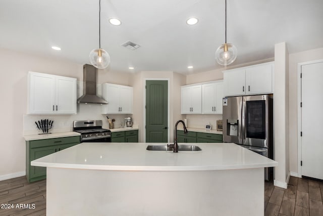 kitchen featuring white cabinets, a center island with sink, appliances with stainless steel finishes, and wall chimney range hood