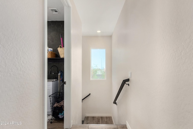 staircase with hardwood / wood-style flooring and sink