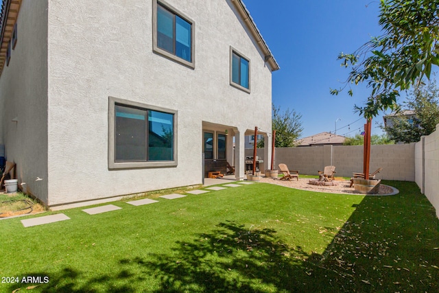 rear view of property with a patio, an outdoor fire pit, and a yard