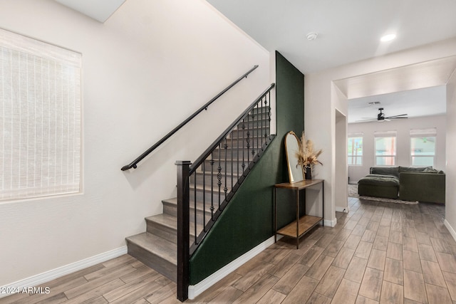 stairway featuring ceiling fan and hardwood / wood-style flooring