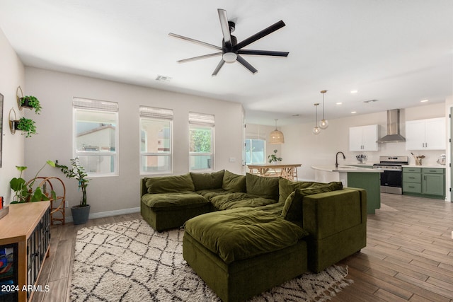 living room featuring light hardwood / wood-style floors, sink, and ceiling fan