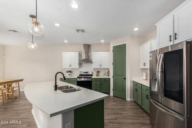 kitchen with appliances with stainless steel finishes, wall chimney exhaust hood, green cabinetry, pendant lighting, and sink