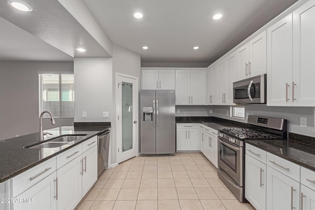 kitchen featuring dark stone countertops, sink, stainless steel appliances, and white cabinets