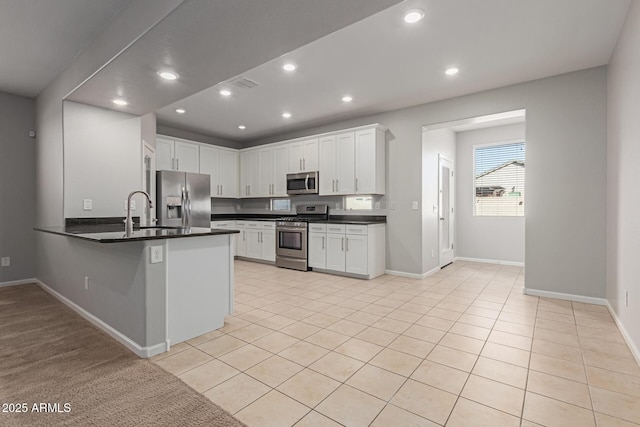 kitchen with light tile patterned flooring, sink, white cabinetry, appliances with stainless steel finishes, and kitchen peninsula