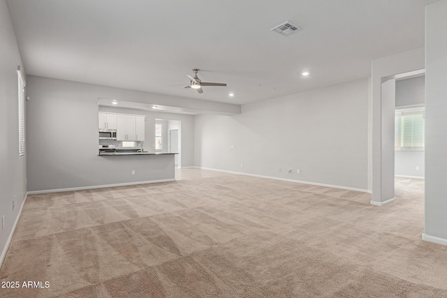 unfurnished living room with light colored carpet and ceiling fan