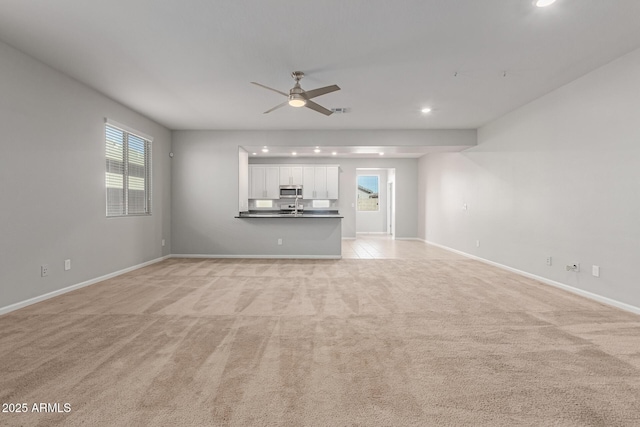 unfurnished living room featuring light carpet and ceiling fan