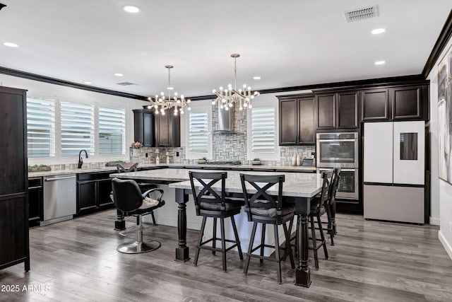 5223 S Axiom, Mesa, AZ 85212 - kitchen featuring appliances with stainless steel finishes, a chandelier, crown molding, a kitchen island, and a breakfast bar