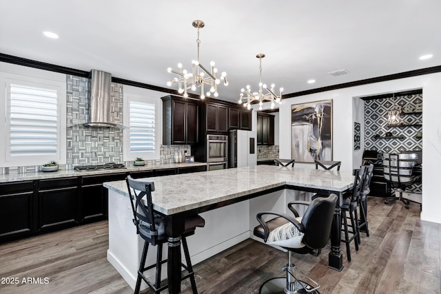 5223 S Axiom, Mesa, AZ 85212 - kitchen featuring wall chimney exhaust hood, a chandelier, stainless steel appliances, ornamental molding, and a breakfast bar area