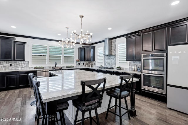 5223 S Axiom, Mesa, AZ 85212 - kitchen featuring stainless steel appliances, wall chimney exhaust hood, a chandelier, tasteful backsplash, and a kitchen island