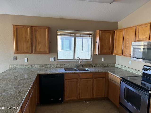 kitchen featuring dark tile patterned flooring, sink, vaulted ceiling, a textured ceiling, and appliances with stainless steel finishes