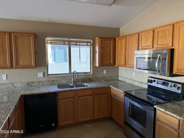 kitchen with a textured ceiling, sink, black appliances, dark tile patterned flooring, and lofted ceiling