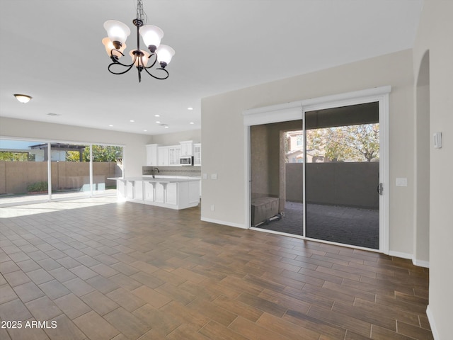 unfurnished living room with sink and a notable chandelier