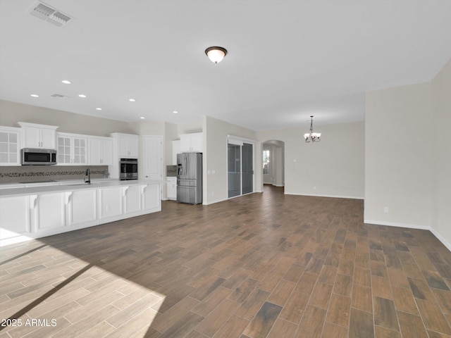 kitchen with sink, white cabinetry, a chandelier, appliances with stainless steel finishes, and decorative backsplash