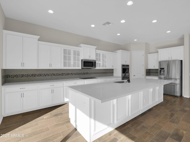 kitchen with appliances with stainless steel finishes, sink, an island with sink, and white cabinets