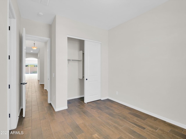 unfurnished bedroom with dark wood-type flooring and a closet