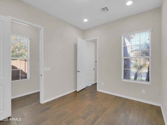 unfurnished bedroom featuring a walk in closet and dark hardwood / wood-style floors