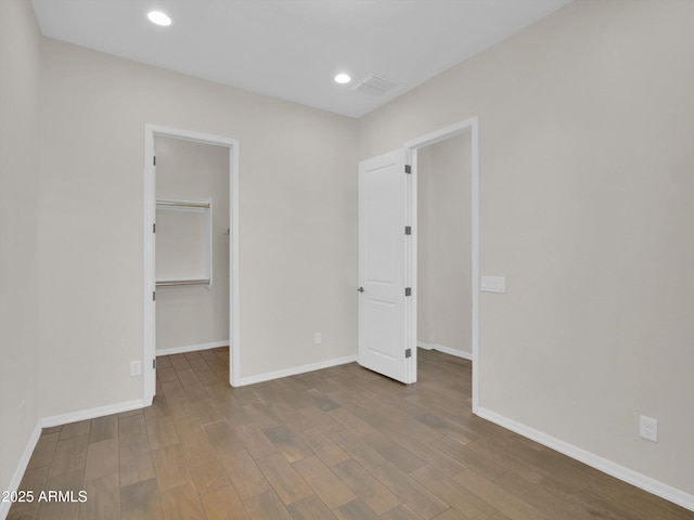 unfurnished bedroom with a walk in closet, hardwood / wood-style floors, and a closet